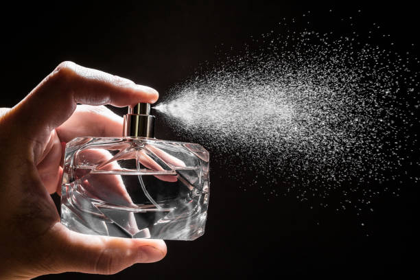 spraying perfume on dark background, closeup image